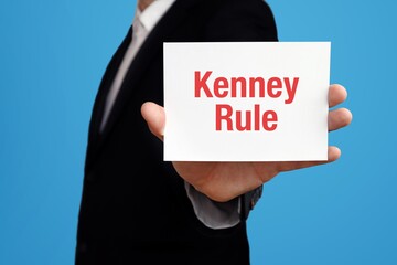 Kenney Rule. Businessman in suit showing business card with text. Man isolated on blue background