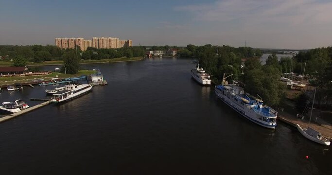 4K high quality calm windless bright summer morning aerial video of Moscow Channel yacht club embankment, green trees, wooden pier and shore with moored anchored boats and yachts near Moscow, Russia