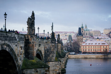 Naklejka premium Karlov or Charles bridge and Vltava River in winter, Panoramic view of Lesser Town (Mala Strana) with bridge towers and baroque Church of St. Nicholas, Prague, Czech Republic