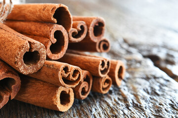 Obraz na płótnie Canvas A close up image of organic cinnamon sticks on a dark wooden table.