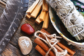 A close up image of a red jasper healing crystal with white sage and palo santo smudge sticks. 