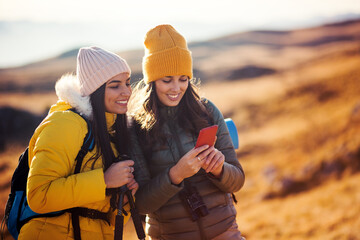 Two girl on hike trip using phone