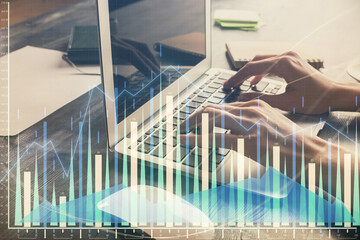Fototapeta premium Double exposure of woman hands typing on computer and forex chart hologram drawing. Stock market invest concept.