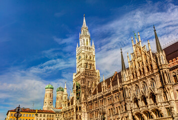 Historic Munich town hall at the Marienplatz with a Frauenkirche in the background on a sunny day.