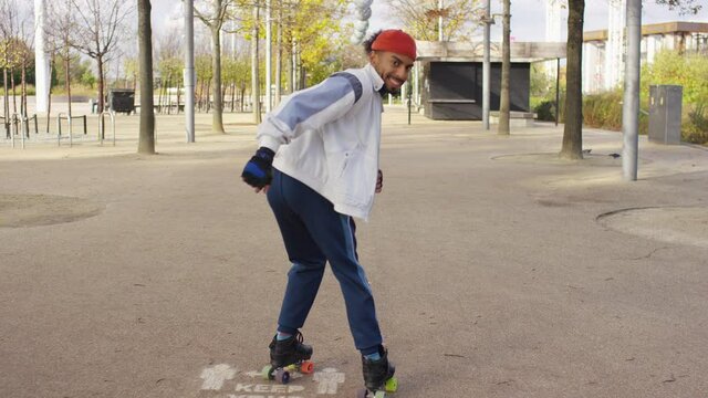 Happy confident male on roller skates skating towards camera, in slow motion 