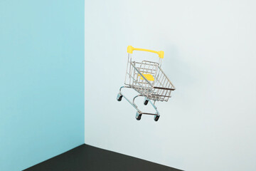 Levitating shopping cart on blue background. Safe online shopping on quarantine concept. Flying Empty supermarket shopping trolley with copy space