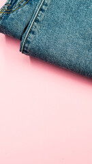 Vertical shot of a pair of jeans on a pink surface
