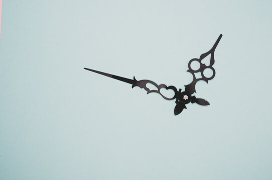 High angle shot of a pair of clock hands on a blue surface