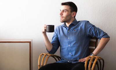 Retrato de un hombre adulto caucásico y apuesto sentado sobre un sillón de mimbre dentro de un...