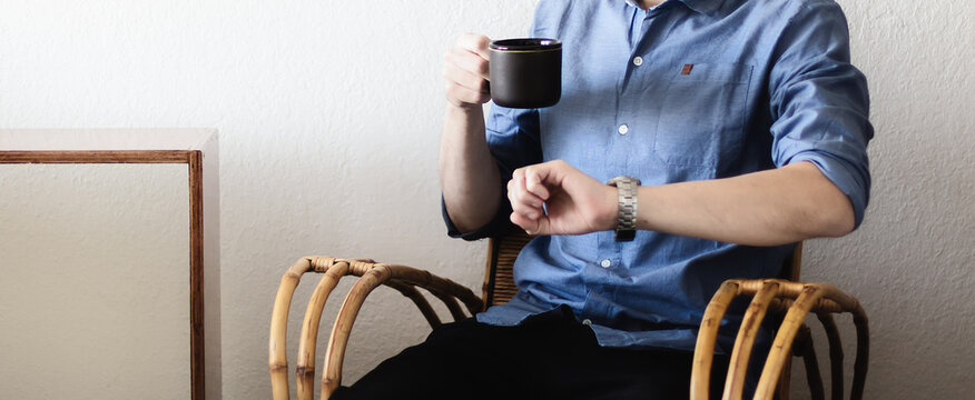 Retrato de parte del cuerpo de un hombre adulto caucásico bebiendo una taza de  café negro sentado en un cálido y confortable apartamento mientras contempla el paso de las horas