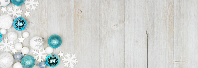 Christmas corner border of blue and white decorations. Above view on a grey wood banner background with copy space.