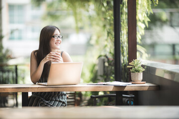 Young female student and freelancer presenting and working at the outdoor cafe with face mask using computer laptop