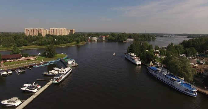 4K high quality calm windless bright summer morning aerial video of Moscow Channel yacht club embankment, green trees, wooden pier and shore with moored anchored boats and yachts near Moscow, Russia