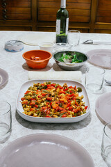 Table with homemade Mexican food. There is a plate with vegetables, corn pancakes, cheeses and salad sprouts. Everything is placed on a white tablecloth.