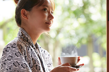 旅館の客室でリラックスをする浴衣姿の若い女性