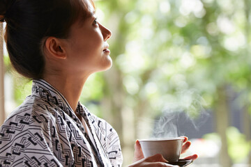 旅館の客室でリラックスをする浴衣姿の若い女性