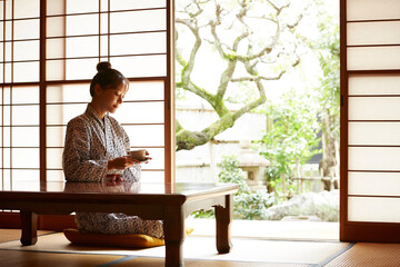 旅館の客室でリラックスをする浴衣姿の若い女性