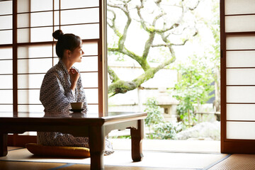 旅館の客室でリラックスをする浴衣姿の若い女性