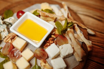 Close-up of a cheese plate. 4 types of cheese, soft white brie cheese, camembert, semi-soft briques, blue, roquefort, hard cheese
