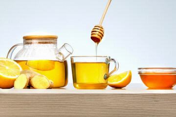 Ginger tea with lemon and honey in glass cup on wooden table.