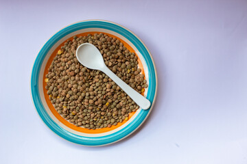 Some lentils and a spoon on a plate.