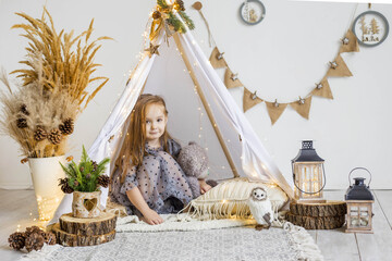 Cute little girl playing with a teddy bear in a wigwam at home.  New Year's decorations.  Happy new year and christmas concept © Наталья Мокрецова