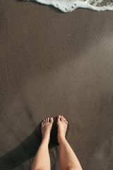 High angle shot of a person standing on the beach near seafoam