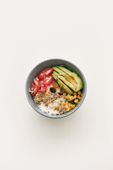 Top view of healthy vegetable bowl lunch with cherry tomatoes, avocado, corn, rice and seeds isolated over white background