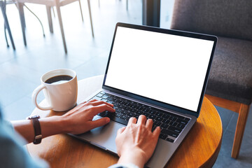 Fototapeta premium Mockup image of a hand typing on laptop computer with blank white desktop screen on the table