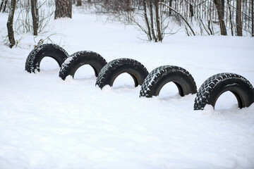 Automobile tire. Five car tires are standing in the snow in the winter forest. The concept of...