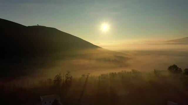 suggestiva ripresa aerea con drone controluce volando sopra una fitta nebbia