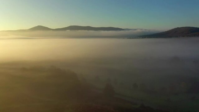 suggestiva ripresa aerea con drone controluce volando sopra una fitta nebbia