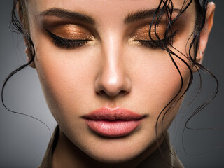 Closeup portrait of a beautiful young fashion woman with glamour makeup posing at studio.