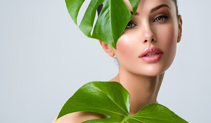 Beautiful woman with green leave near face and body.  Closeup girl's face with green leave. Skin care beauty treatments concept.