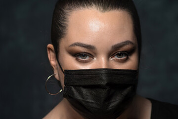 portrait of a beautiful woman in a black mask on a dark background. close up