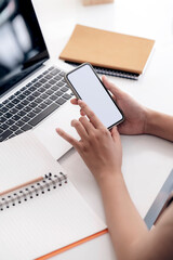 Cropped shot of female hands using smartphone while sitting at her office desk.