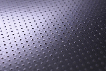 Dark industrial metallic background. Tinted violet or purple wallpaper. Perforated aluminum surface with many holes. Perforation rows go into the distance and form a perspective. Macro