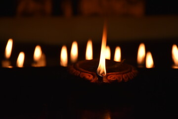 Clay Diya or Oil Lamp lits during the Diwali night. Traditional Diyas lit on gold and black background