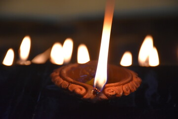 Fototapeta premium Clay Diya or Oil Lamp lits during the Diwali night. Traditional Diyas lit on gold and black background