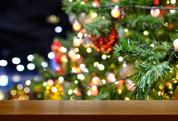 Christmas and New Year concept. Wooden table top with Christmas tree with decorations blurred from the celebration. Can be used for display or montage your products.