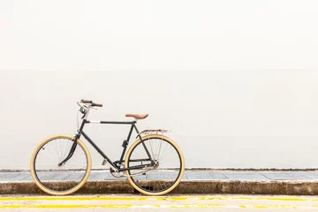 Wall murals Bike bicycle on the street. Black Vintage Hipster Bicycle With White Tires On A Quiet Street, By A White Wall