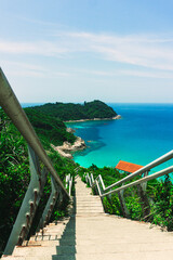 The beautiful scenic view of Small Perhentian Island in Terengganu, Malaysia. The wide view of ocean and green island from the peak of hill. The concrete stairs lead the way to the abandoned jetty.