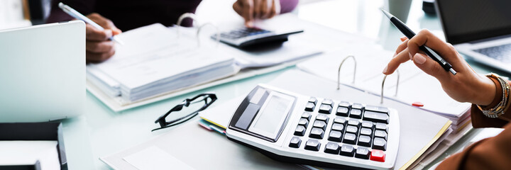 Two Businessman Using Calculator At Workplace