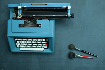 Fototapeta na wymiar macchina da scrivere su lavagna con pennelli per il make up