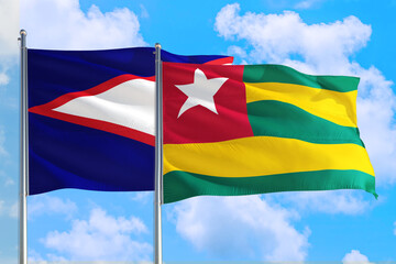 Togo and American Samoa national flag waving in the windy deep blue sky. Diplomacy and international relations concept.