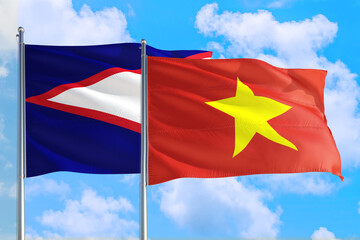 Vietnam and American Samoa national flag waving in the windy deep blue sky. Diplomacy and international relations concept.