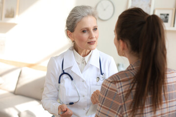 Friendly middle aged female doctor encouraging, supporting patient after medical examination.