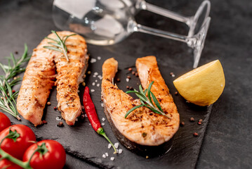 Dinner for two. Grilled salmon steaks, bottle of wine and glasses on stone background. View from above