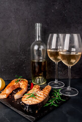 Dinner for two. Salmon steaks, a bottle of white wine and glasses on a stone background.