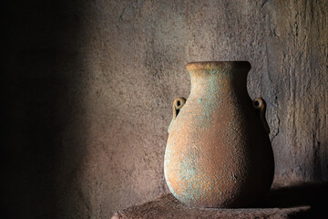 Drinking earthenware jug on stone shelf indoors.